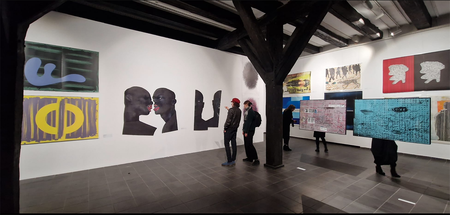 Widok wystawy w Galerii Wozownia w Toruniu, dwie osoby przyglądające się pracom