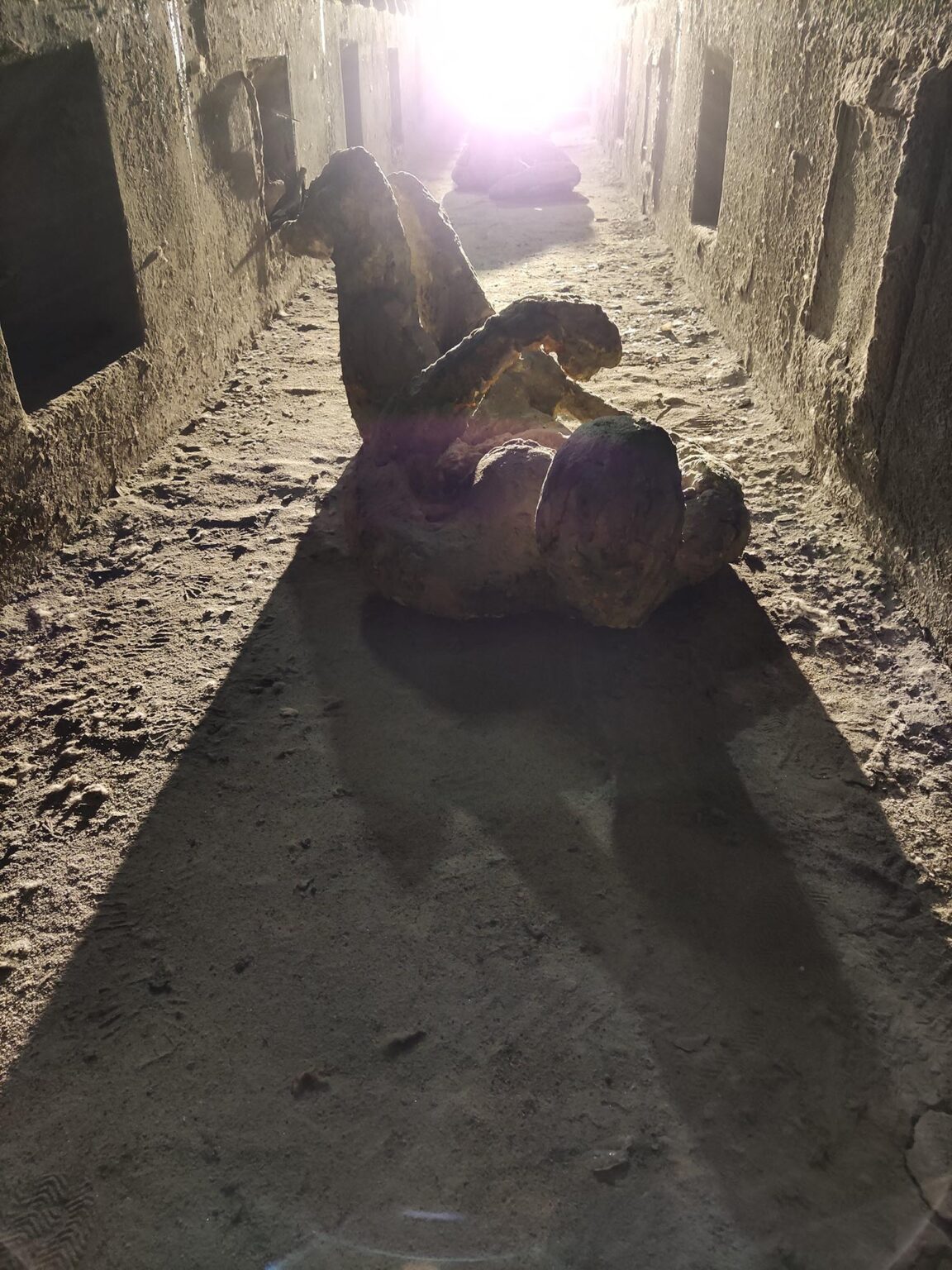 Korytarz, w którym leży rzeźba przedstawiająca skulonego człowieka