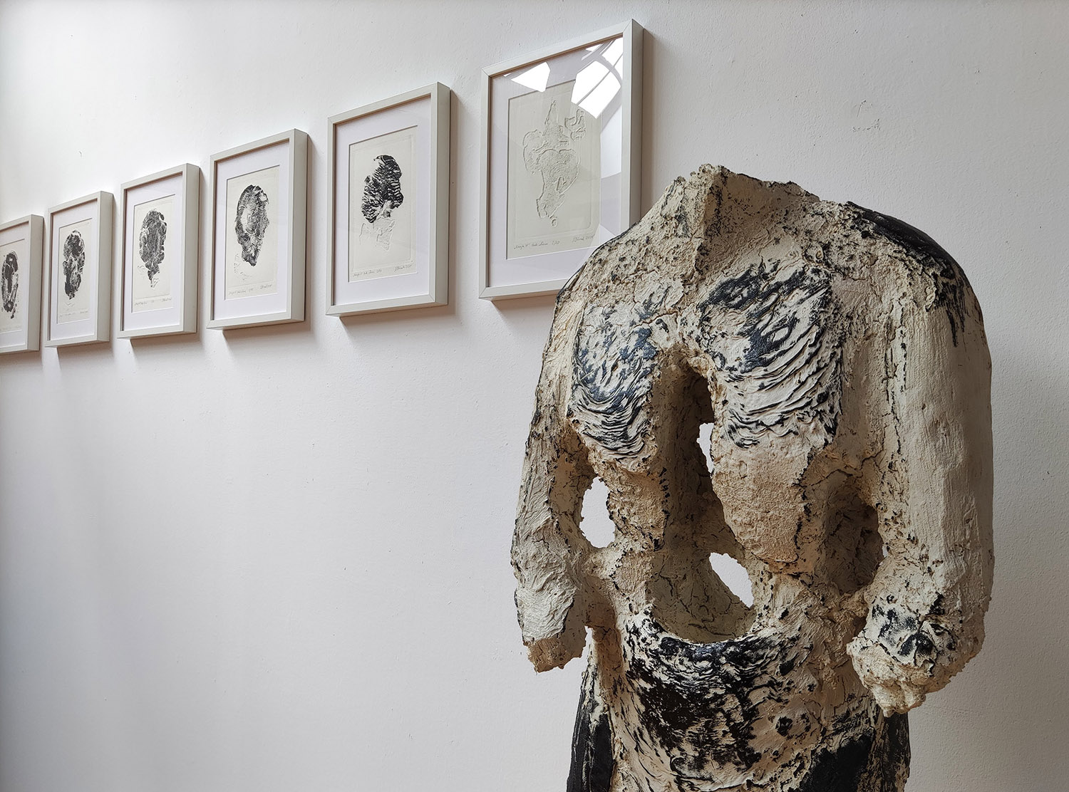 Widok wystawy, na pierwszym planie rzeźba, na drugim odbitki graficzne w ramkach