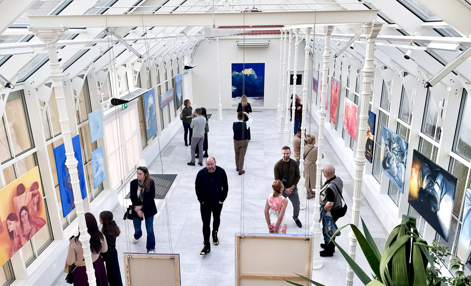 Widok wystawy z góry, ludzie oglądający obrazy