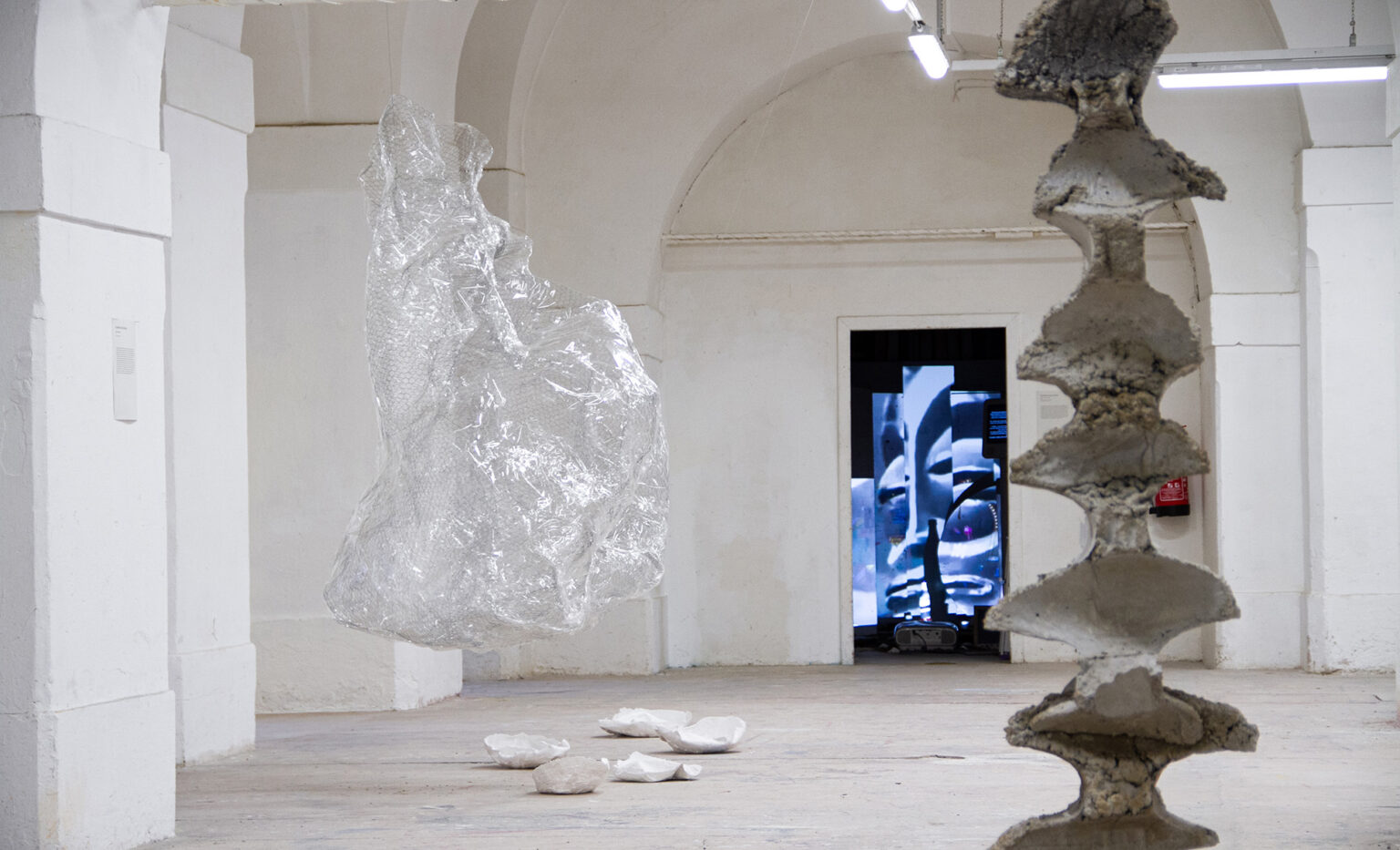 Widok wystawy, na pierwszym planie kolumna, na drugim abstrakcyjny kształt