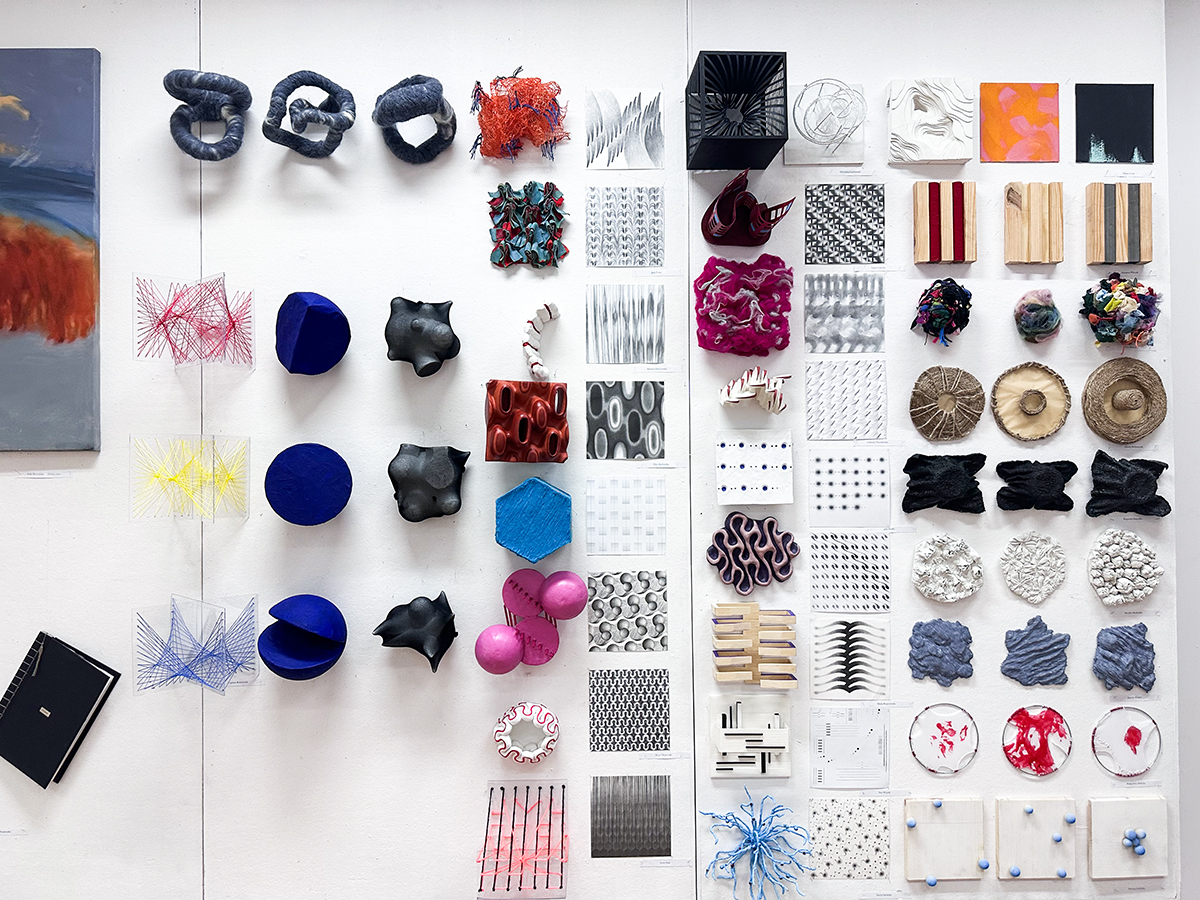 Wieloelementowa kompozycja prac w małym formacie na białej ścianie