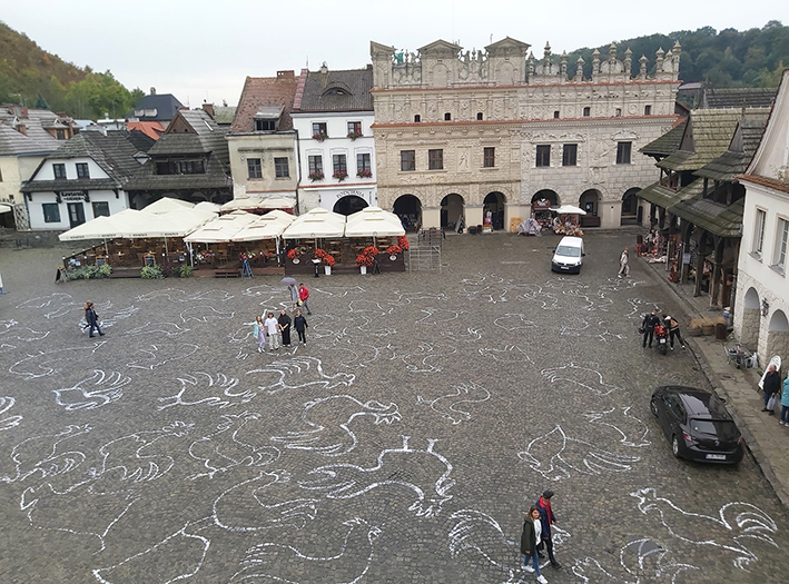 Widok rynku w Kazimierzu Dolnym, widziany z góry. Na kostce narysowano kredą liczne koguty - symbol miasta.