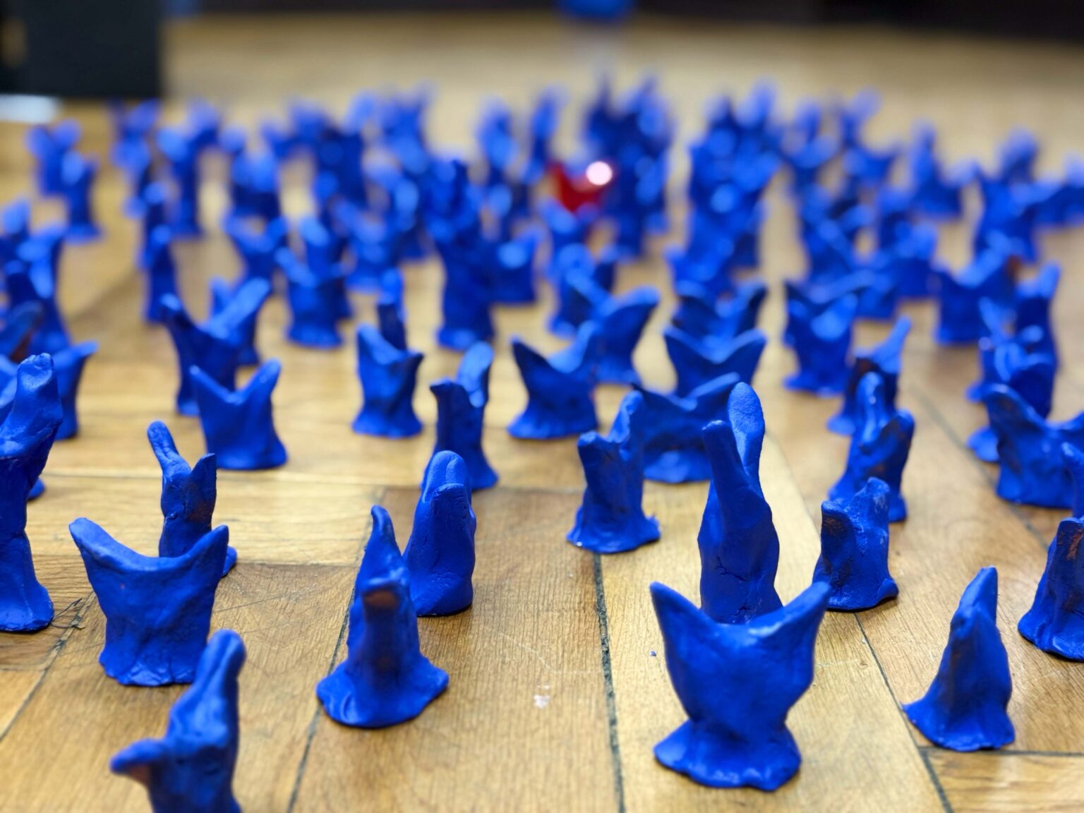 Abstrakcyjne figurki w kolorze ultramarynowym i jedna czerwona stojące na podłodze