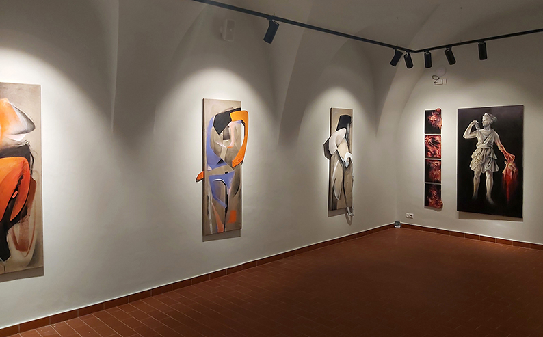 Widok wystawy w muzeum, pięć wertykalnych kompozycji na ścianach.