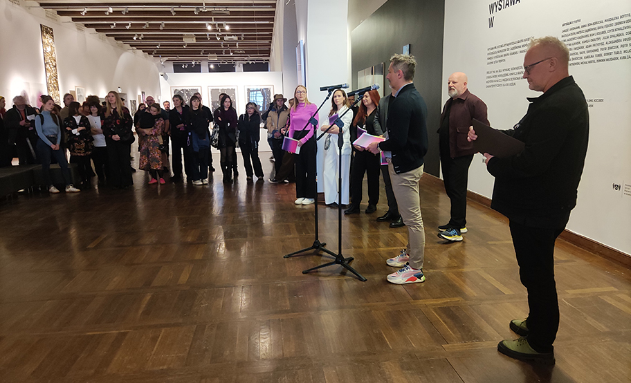 Otwarcie wystawy WG, kilka osób stojących z mikrofonami przed publicznością