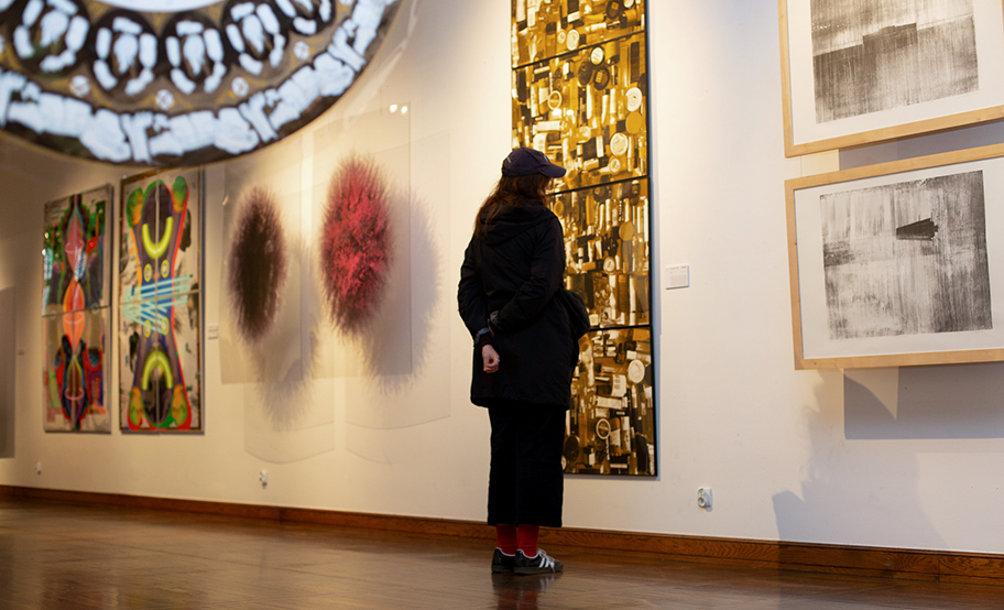 Jedna osoba oglądająca podłużną, żółtą grafikę na wystawie WG