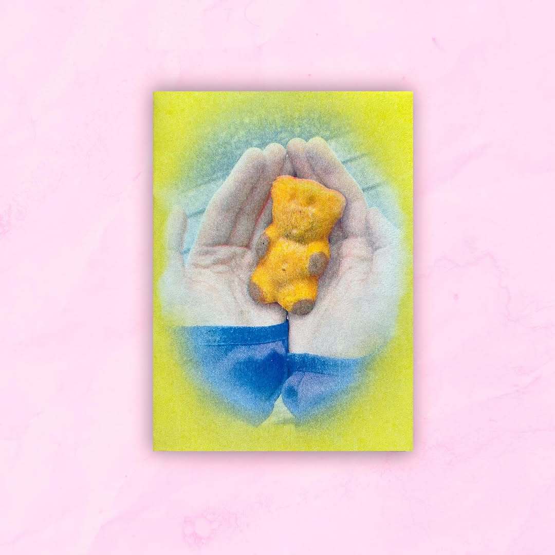 Dwie złożone ręce, na których leży żelkowy miś Haribo w kolorze żółtym