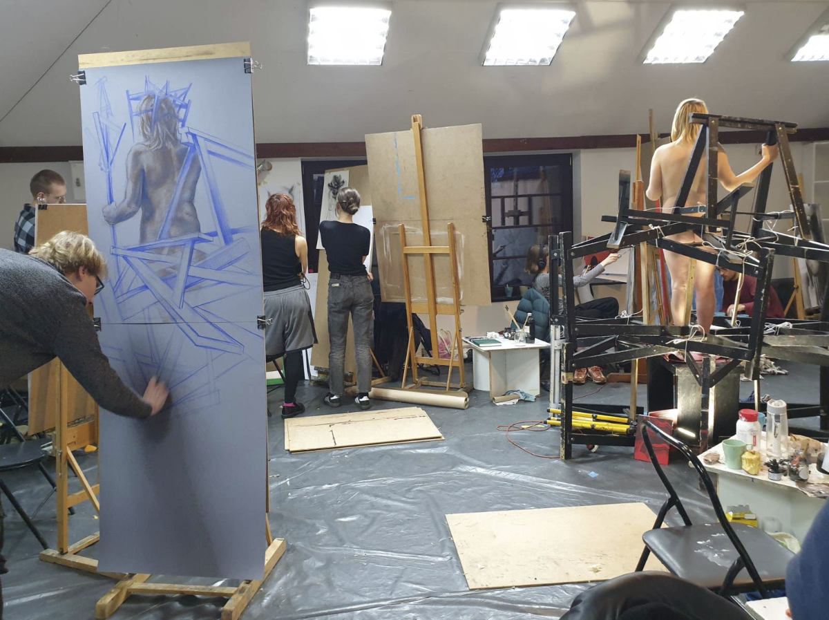 Studenci rysujący przy sztalugach na warsztatach