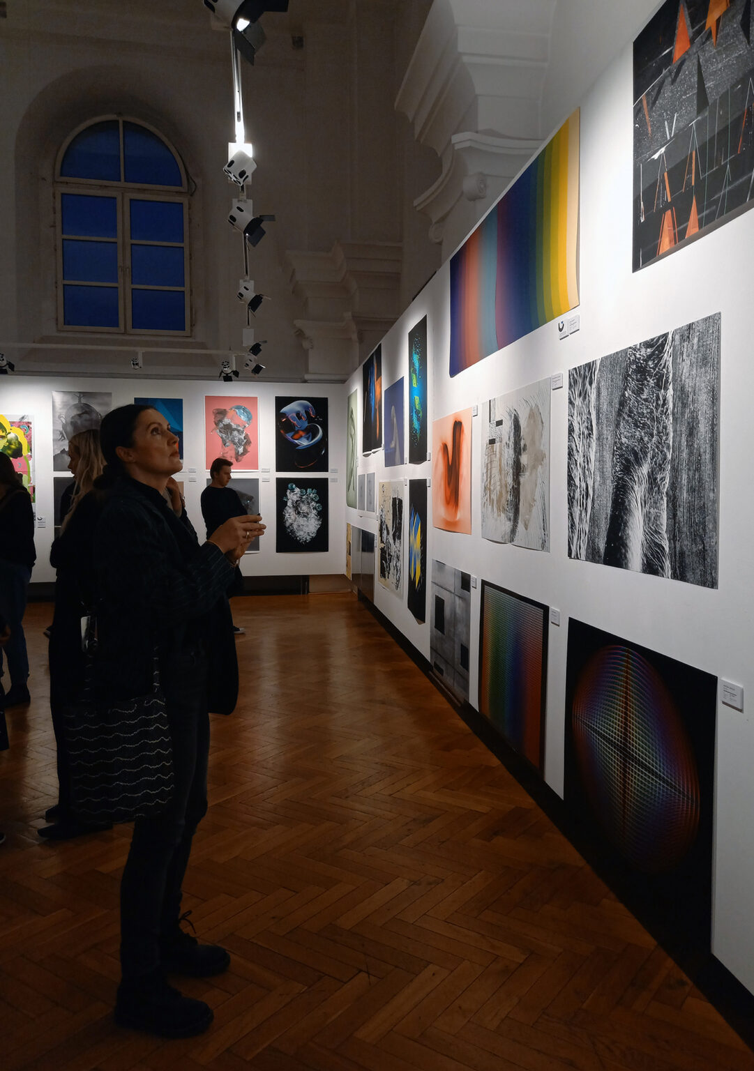 Kobieta ogląda wiszące na ścianie grafiki.