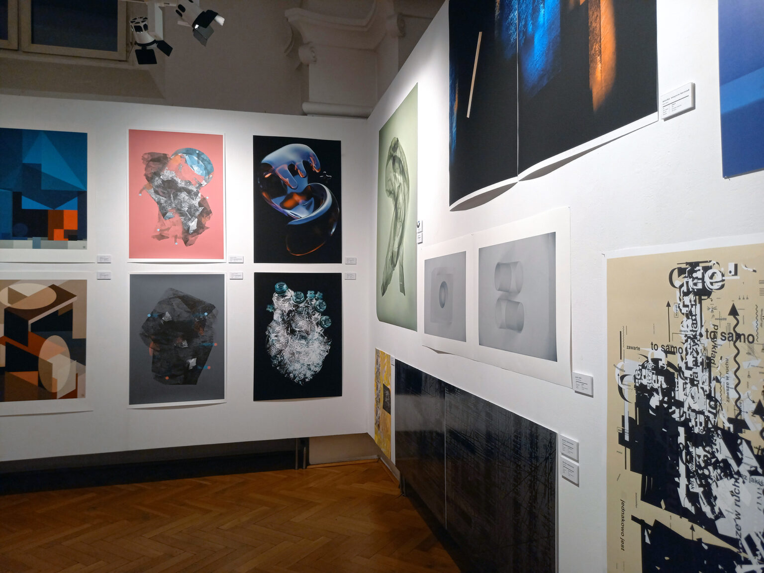 Widok prac graficznych wiszących na ścianie po prawej stronie i na wprost obiektywu.