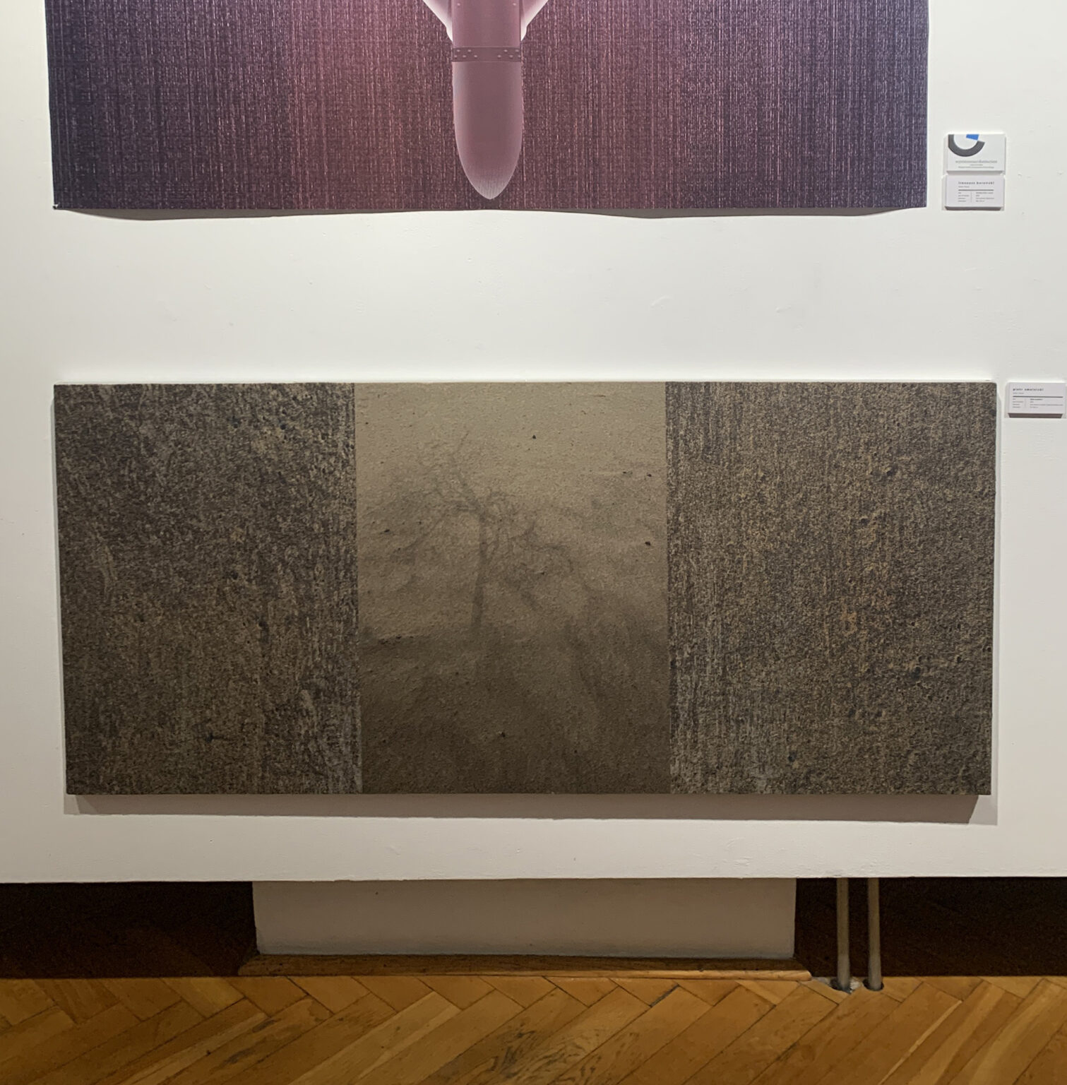 Widok ściany z dwiema grafikami przedstawiającymi abstrakcyjne pejzaże.