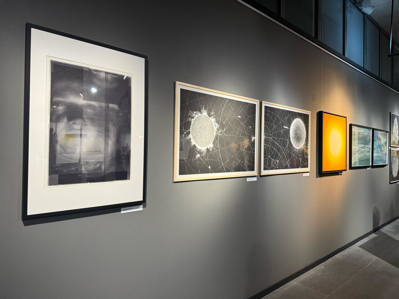 Widok czterech prac na ścianie galerii podczas wystawy (3 grafiki i 1 obraz).