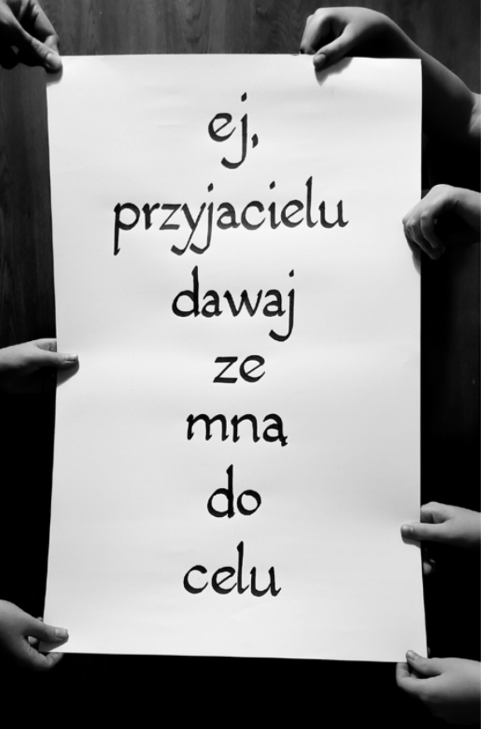 Tekst kaligrafowany na papierze, trzymanym po bokach przez 7 rąk