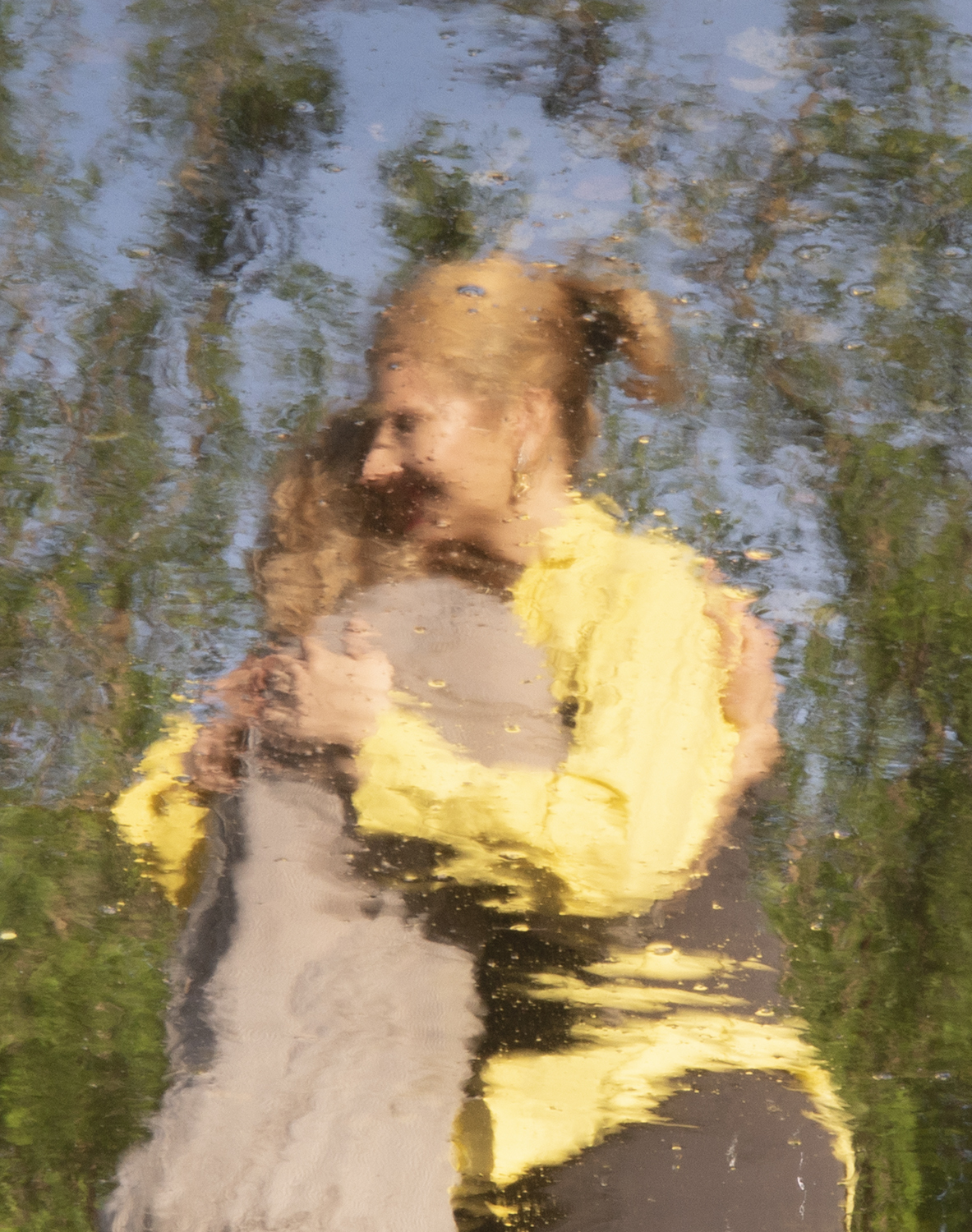 Fotografia przedstawiająca dwie przytulone postaci, odbite w wodzie
